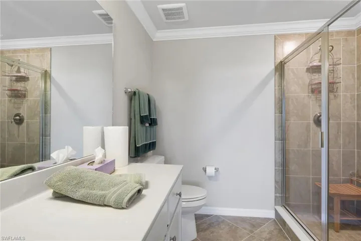 Full bath with ornamental molding, a shower stall, vanity, and light tile patterned flooring