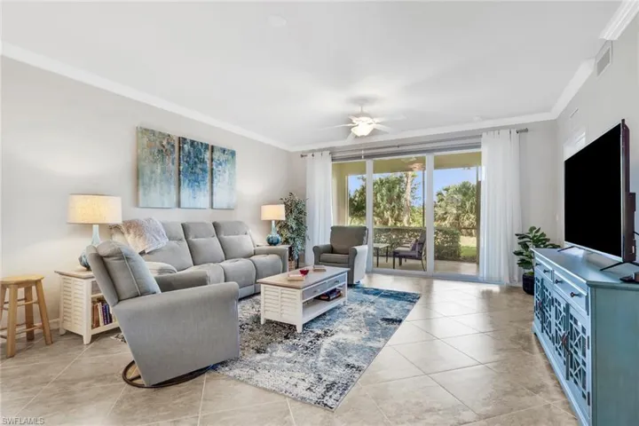 Living room featuring crown molding, ceiling fan, and light tile patterned floors