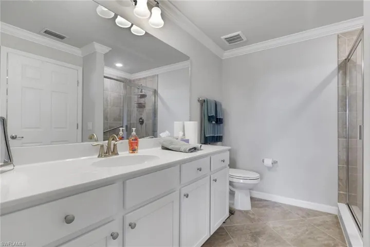 Bathroom with vanity, a stall shower, ornamental molding, and light tile patterned floors