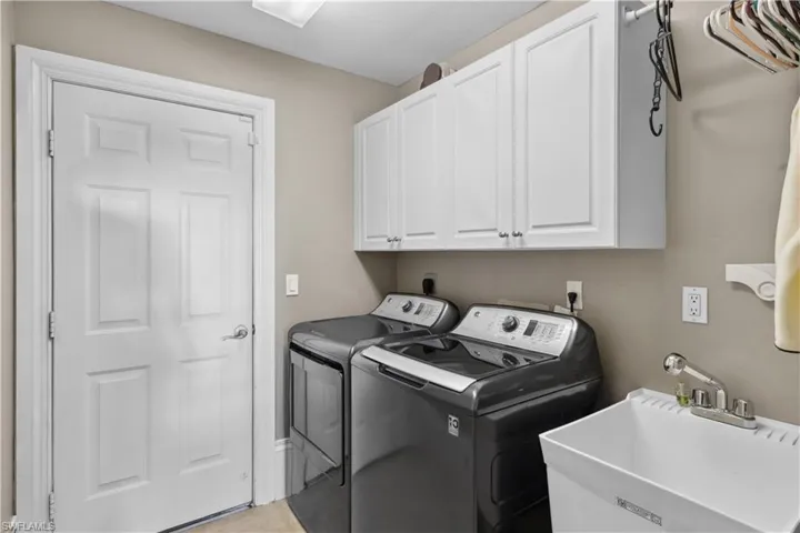 The laundry room is a functional space featuring a deep laundry tub, modern washer and dryer, and storage cabinets for convenience.