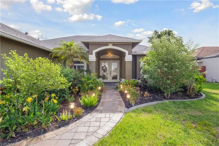 A beautifully landscaped front yard sets the tone as you approach the entryway, where vibrant greenery and mature plants frame a charming front porch and elegant front door.