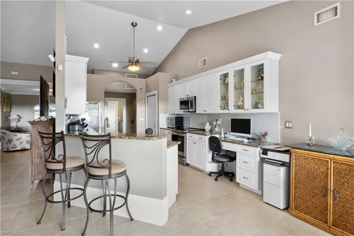 Alongside the sleek cabinetry, granite countertops, and stainless-steel appliances, a built-in desk area is seamlessly integrated into the layout.