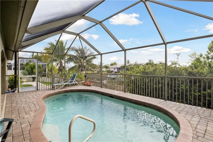 The surrounding space is enhanced by lush landscaping, creating a serene atmosphere for lounging or enjoying meals by the pool. It’s the perfect retreat for outdoor living, day or night.