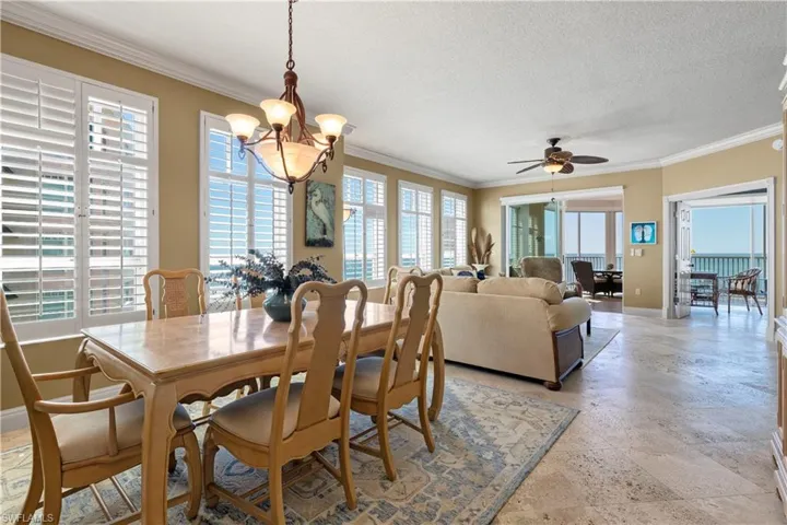Dining space featuring crown molding, ceiling fan, a chandelier, and a textured ceiling
