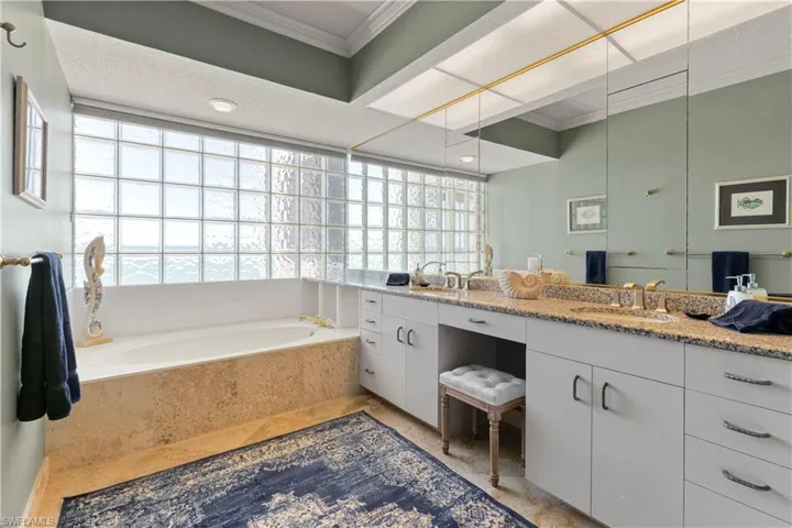 Bathroom with double vanity, ornamental molding, a garden tub  and linen closet