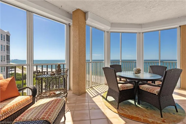 Lanai featuring view of water and beach, plenty of natural light, and a textured ceiling as well as hurricane motorized shutters