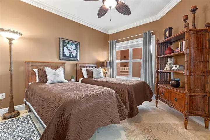 Bedroom with large walk-in closet, crown molding, a ceiling fan and travertine tile