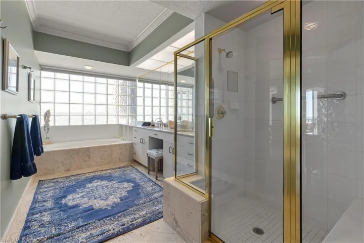 Full bath with vanity, a garden tub with separate walk-in shower, textured ceiling, ornamental molding, and a shower stall