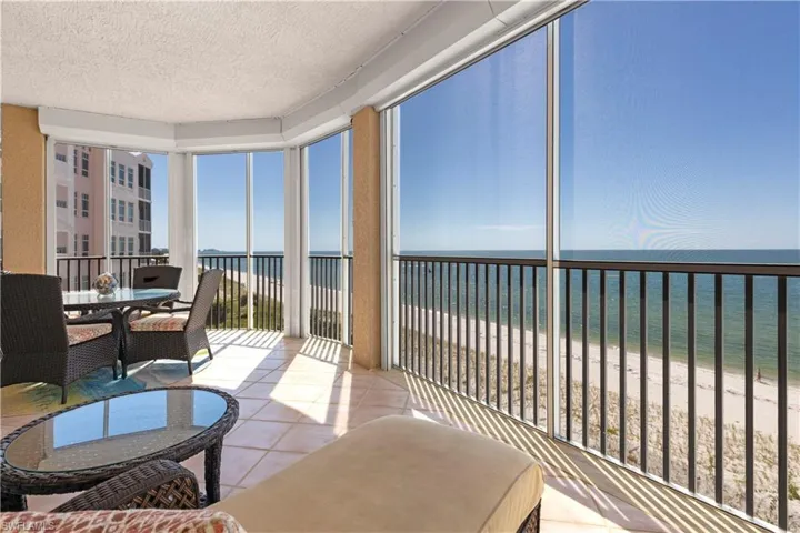 Lanai with view of the Gulf water, expansive beach views, patterned tile flooring, a textured ceiling, and screens