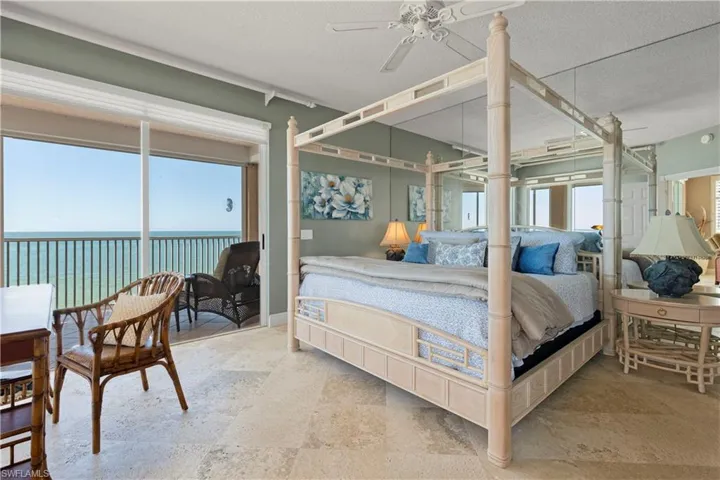 Bedroom featuring a water view, access to exterior, ceiling fan, a textured ceiling, and stone finish flooring