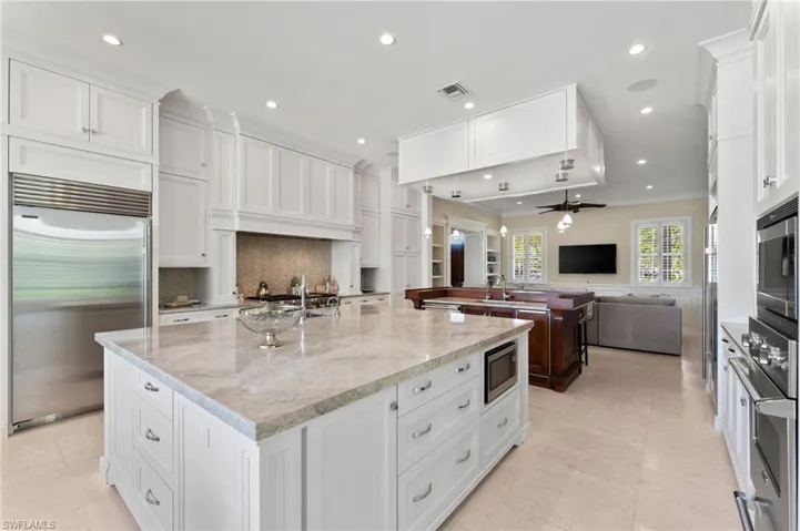Kitchen with built in appliances, ornamental molding, open floor plan, visible vents, and a large island with sink
