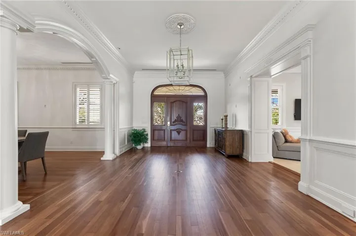 Foyer entrance with decorative columns, arched walkways, wood finished floors, and a healthy amount of sunlight