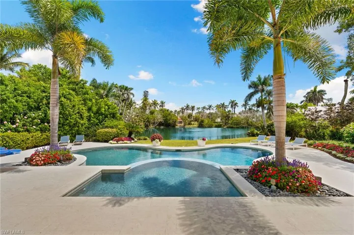 Outdoor pool with a patio area, an in ground hot tub, and a water view