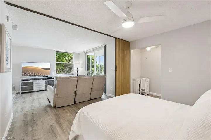 Wood-finish flooring, ceiling fan, and large windows with natural light