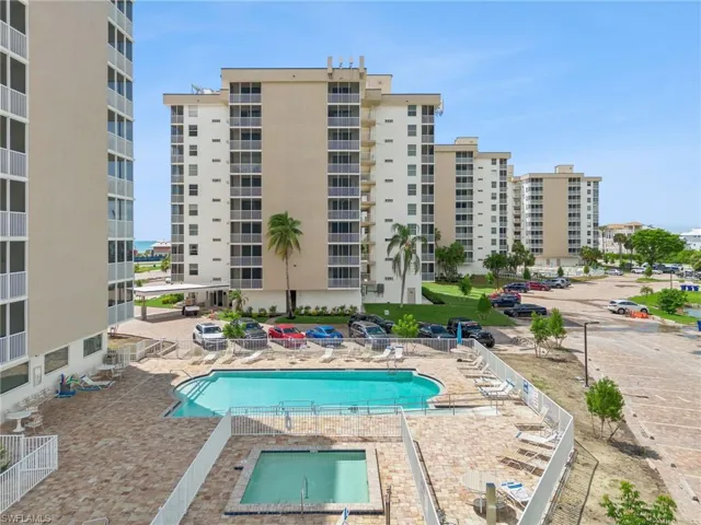 Outdoor swimming pool with surrounding paver decking, adjacent spa, and multiple residential towers