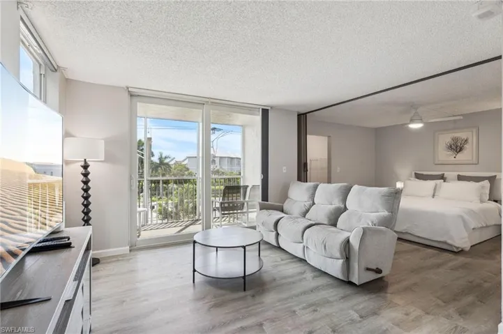 Open-concept living area with wood-finish flooring, sliding glass balcony doors, and recessed ceiling lighting