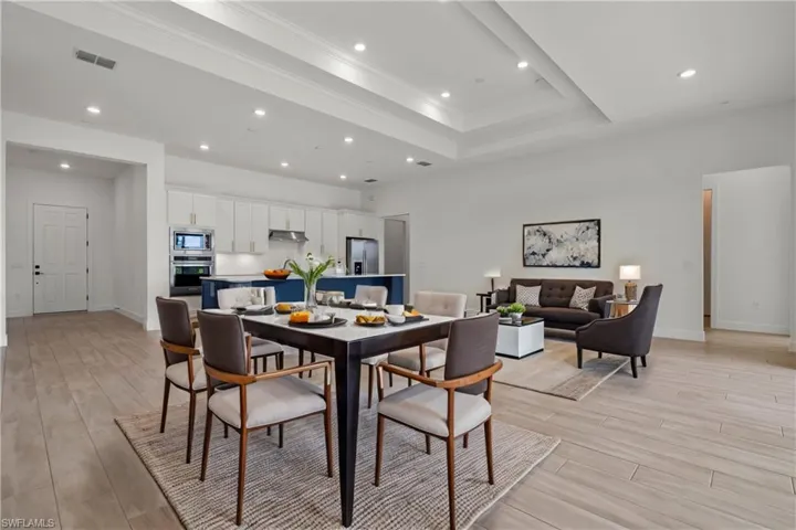 Dining space with crown molding, a tray ceiling, and light wood-type flooring
