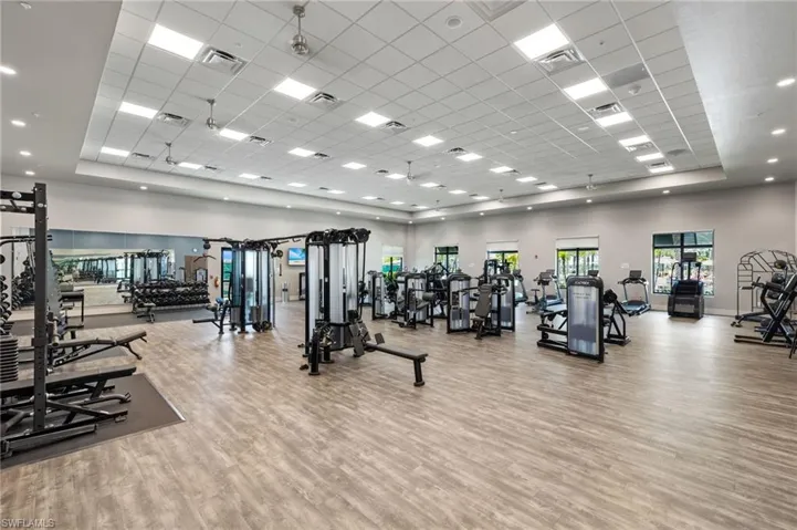 Exercise room featuring a towering ceiling, a paneled ceiling, and light hardwood / wood-style floors
