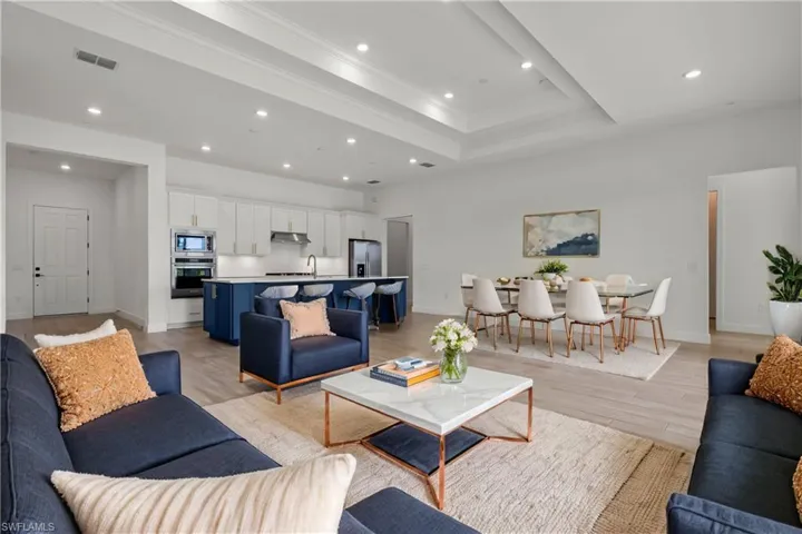 Virtually Staged Living room with crown molding, a tray ceiling, sink, and light wood-type flooring