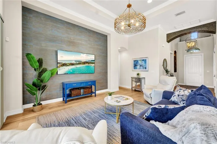Living room with hardwood / wood-style floors, an inviting chandelier, and ornamental molding