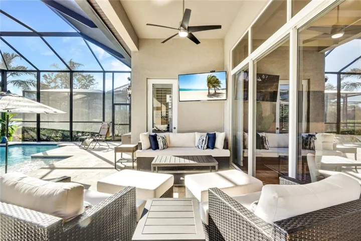 View of patio / terrace with an outdoor living space, glass enclosure, and ceiling fan