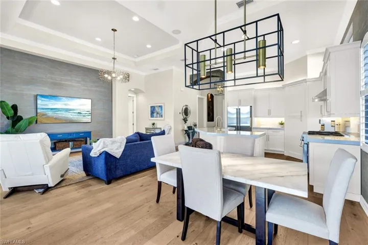 Dining space with a raised ceiling, an inviting chandelier, light hardwood / wood-style flooring, and ornamental molding