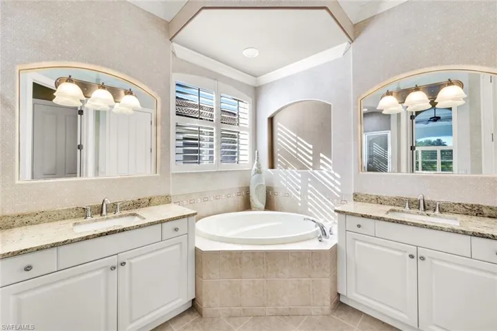 Bathroom featuring tile patterned flooring, vanity, crown molding, and tiled tub
