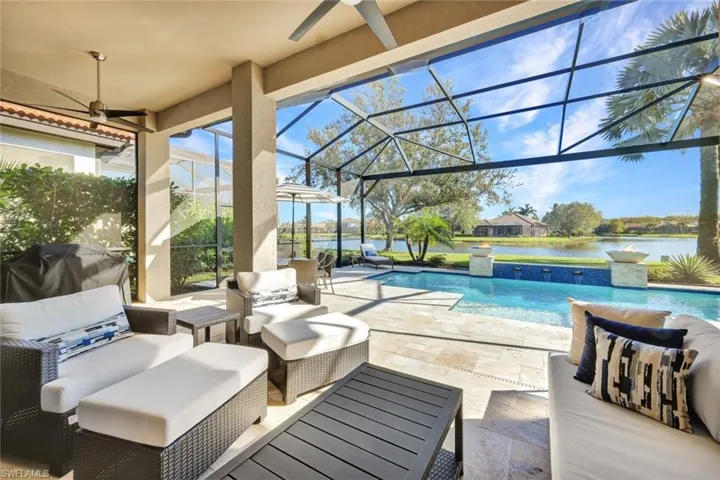 View of patio / terrace featuring glass enclosure, a water view, an outdoor hangout area, pool water feature, and ceiling fan