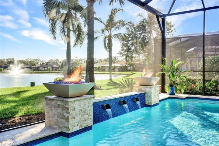 View of swimming pool featuring pool water feature, a lanai, a water view, and a lawn