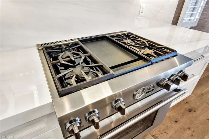 Room details with white cabinets, hardwood / wood-style floors, and high end stove