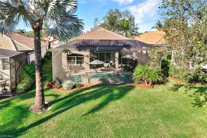 Back of property with a lanai and a lawn