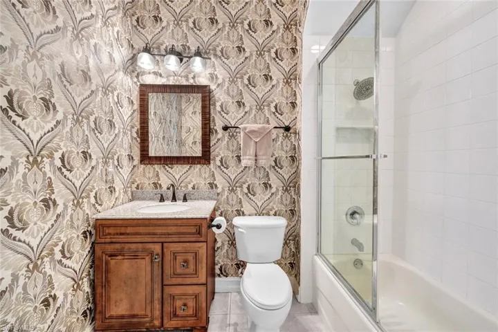 Full bathroom featuring tile patterned flooring, vanity, combined bath / shower with glass door, and toilet