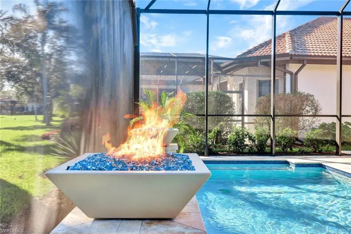 View of pool featuring glass enclosure and a fire pit
