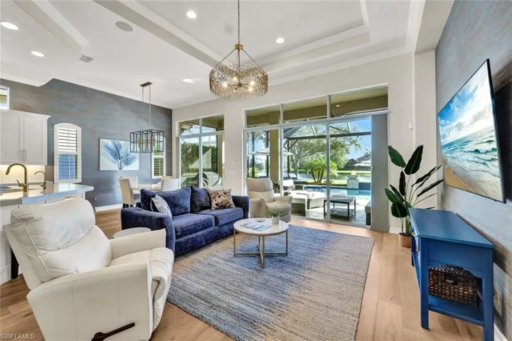 Living room featuring a chandelier, light wood-type flooring, a tray ceiling, and sink