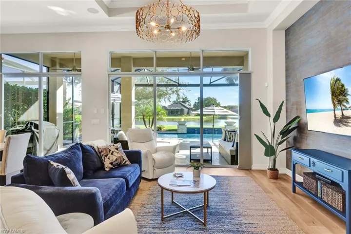 Living room with a tray ceiling, crown molding, light hardwood / wood-style flooring, and an inviting chandelier