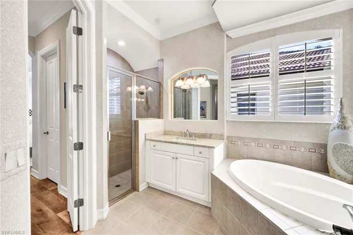 Bathroom with plus walk in shower, vanity, hardwood / wood-style flooring, and crown molding