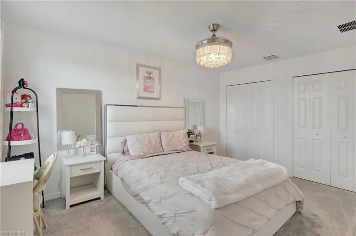 Bedroom with carpet floors, a notable chandelier, multiple closets, and visible vents