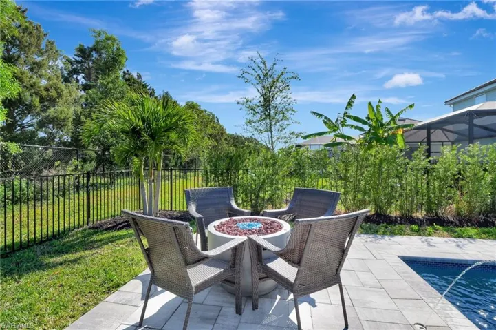 View of patio with an outdoor fire pit, fence, and a fenced in pool
