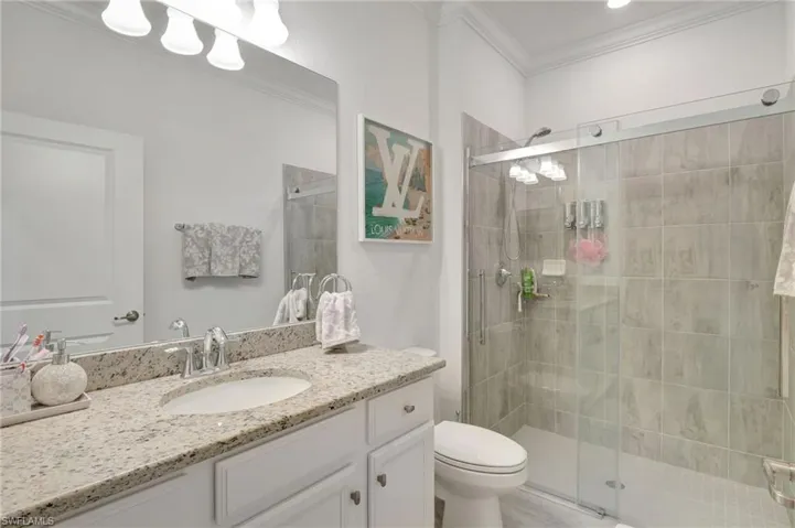 Full bath with a stall shower, toilet, vanity, and ornamental molding