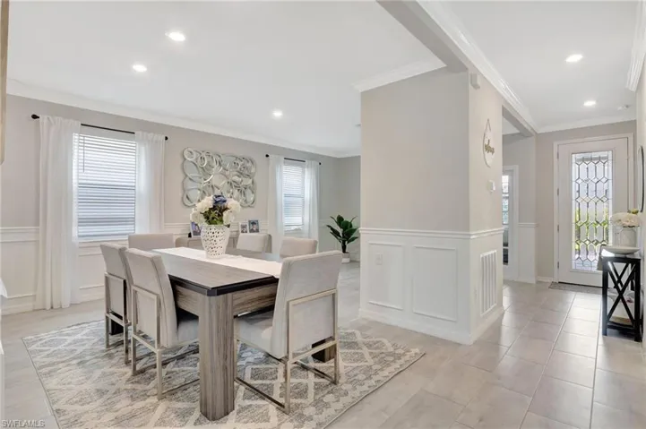Dining space featuring wainscoting, crown molding, and a decorative wall
