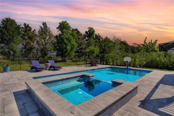 View of swimming pool featuring a patio, fence, and a pool with connected hot tub