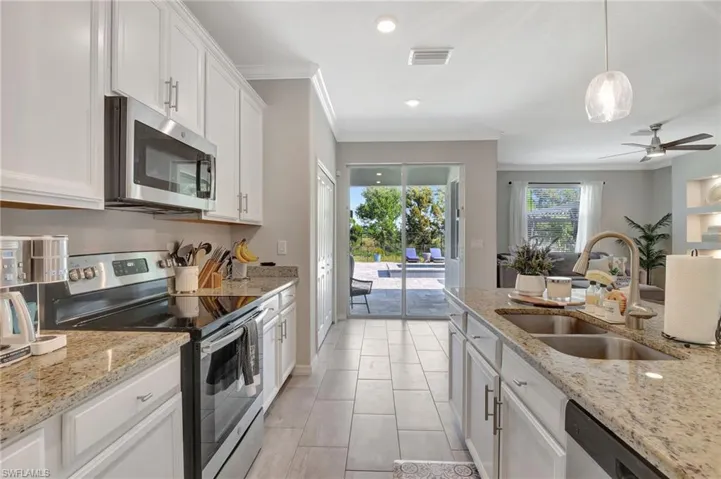 Kitchen with a sink, stainless steel appliances, visible vents, white cabinets, and ornamental molding