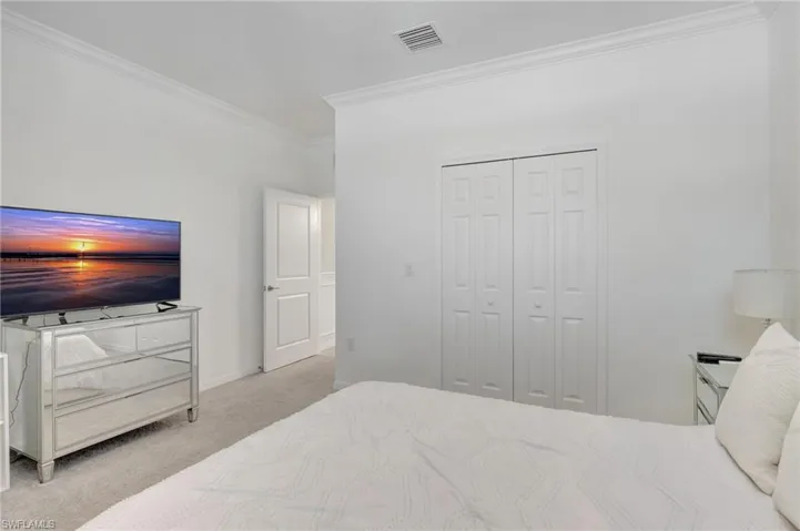 Carpeted bedroom featuring baseboards, visible vents, a closet, and ornamental molding