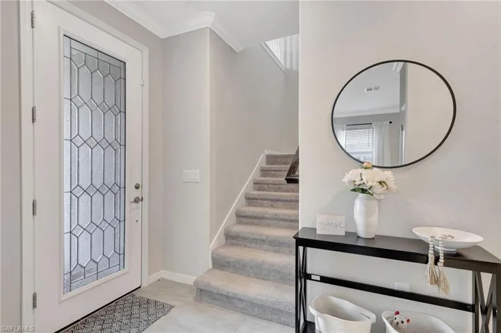Foyer entrance featuring visible vents, baseboards, ornamental molding, stairway, and tile patterned flooring