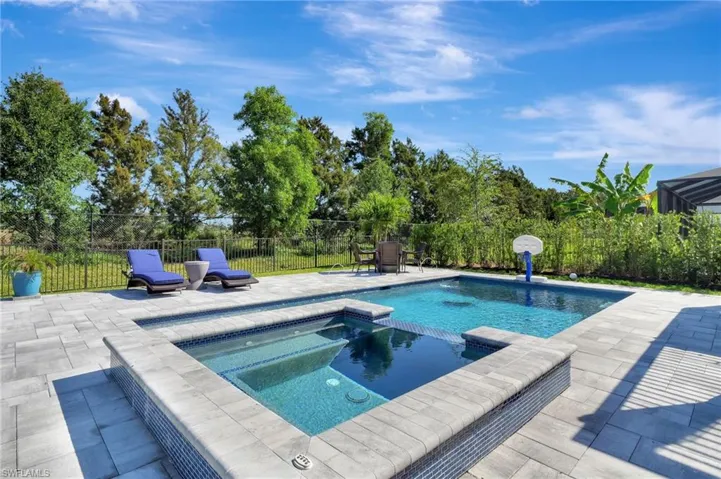 View of swimming pool with a pool with connected hot tub, fence, and a patio