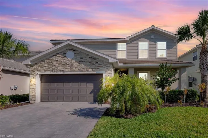 Traditional-style home with decorative driveway, stone siding, and a garage