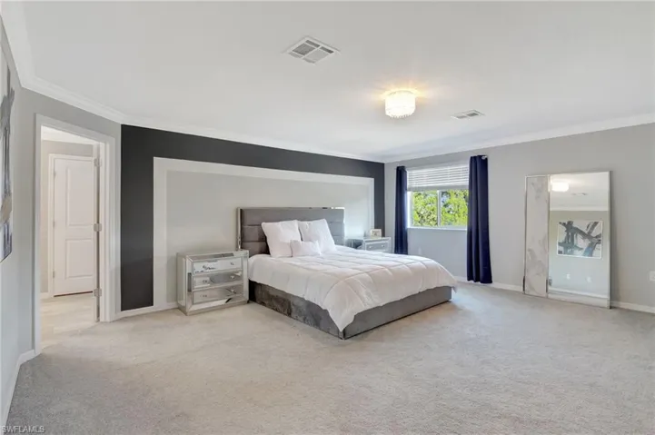 Bedroom featuring baseboards, ornamental molding, visible vents, and light carpet