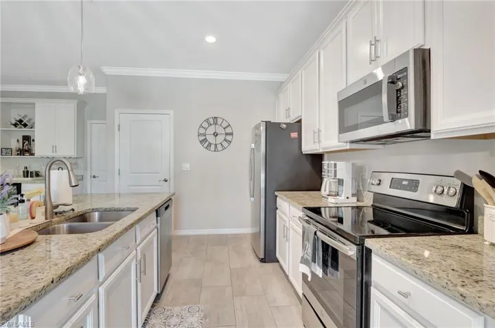Kitchen featuring crown molding, a sink, white cabinetry, stainless steel appliances, and baseboards