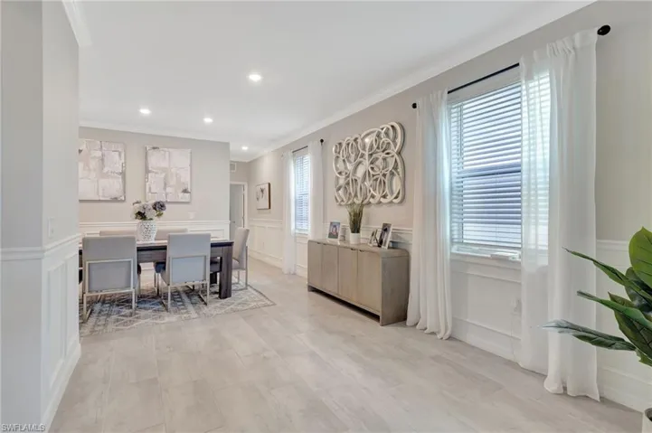 Dining area featuring a wainscoted wall, ornamental molding, a decorative wall, and recessed lighting