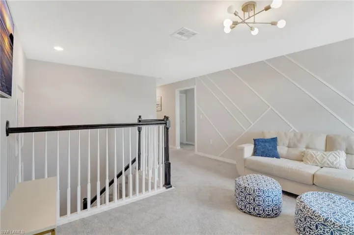 Living area featuring a notable chandelier, carpet, an upstairs landing, visible vents, and recessed lighting